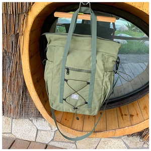 Detail of light green travel tote bag featuring functional drawstring and zip pocket