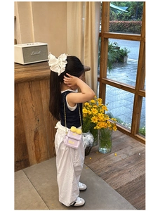Détail du mini sac à chaîne violet avec nœud jaune et accessoire cheveux en dentelle