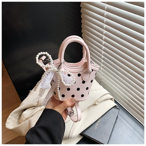 Détail du mini sac rose à pois avec nœud en perles et breloque en dentelle au soleil