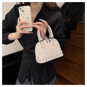 Detail of mini ivory dome bag featuring crocodile pattern texture and silver metal rivets