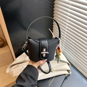 Detail der schwarzen Mädchenhandtasche mit Webstruktur und süßem Puppenanhänger