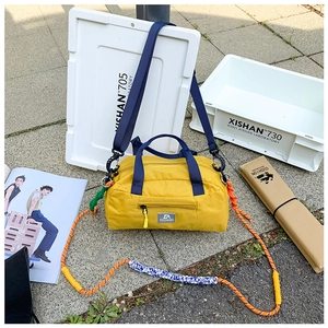 Detail of yellow nylon travel bag with orange climbing rope handle and blue strap