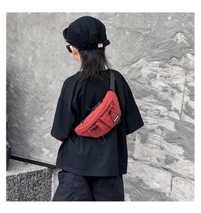 Outdoor shot of kid red canvas chest bag with black bungee cord and adjustable strap