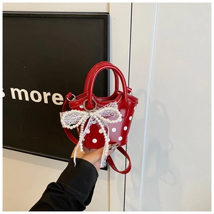 Gros plan du mini sac rouge à pois avec nœud décoratif en perles et dentelle brillante