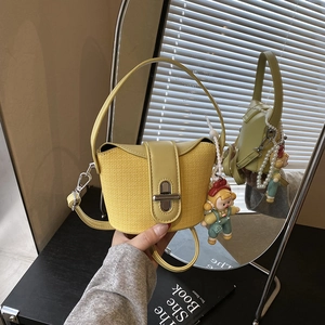 Gelbe Patchwork-Minihandtasche mit süßem Puppenanhänger und Perlenkette im Detail