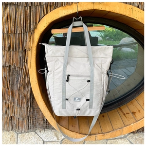 Detail of light grey kids travel bag with drawstring and zipper pocket on wood wall