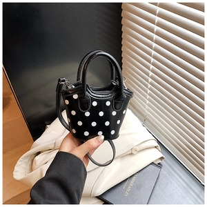 Détail du mini sac seau en cuir noir à pois blancs avec double poignée et bandoulière