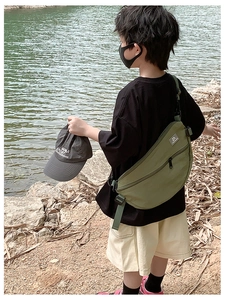 Sac bandoulière vert en nylon pour garçons avec sangle réglable sur fond naturel