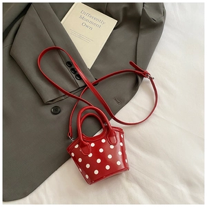 Détail du mini sac seau rouge à pois avec finition brillante et bandoulière longue assortie