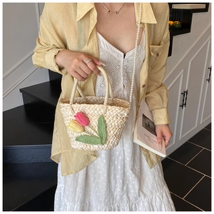Detailed texture of straw bucket bag with crochet tulip flowers and pearl chain