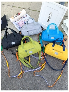 Detailed flat lay of colorful nylon sports duffel bags with contrast braided shoulder straps