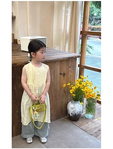 Toddler girl modeling light yellow sleeveless dress with green mini handbag