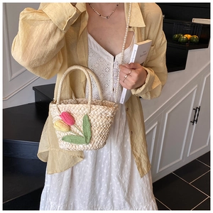 Detail of handmade floral straw bag with pearl chain and crochet tulip decorations