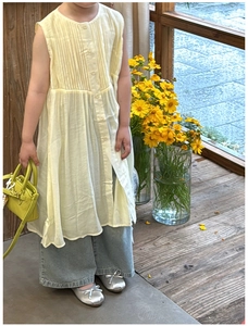 Detail of lime green mini child handbag styled with a pale yellow cotton shirt dress