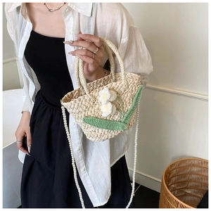 Close-up of handmade straw shoulder bag with crochet flowers and pearl chain detail