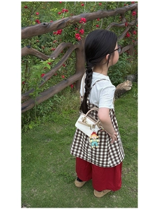 Close-up of a stylish kids mini shell handbag with a cute doll charm and red floral accents