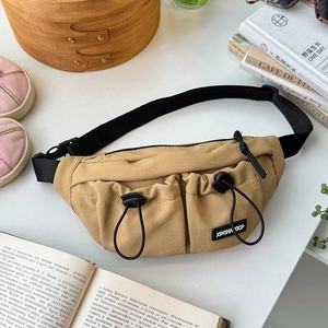 Detail of khaki nylon kids chest bag featuring dual drawstring pockets and black logo