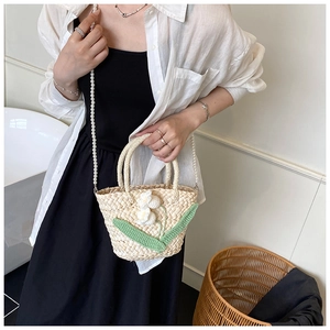 Detail of handmade straw beach bag with lily of the valley crochet and pearl strap