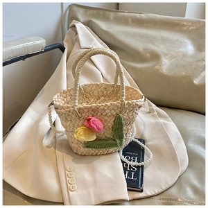 Detail of a beige woven straw bag featuring crochet tulips and a pearl chain strap