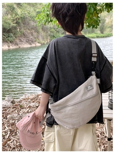 Détail d'un sac bandoulière en nylon kaki en forme de croissant avec poche zippée