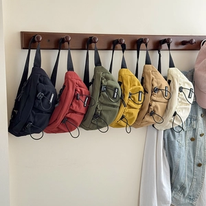 Detail of colorful canvas waist bags for kids hanging on a row of wooden wall hooks