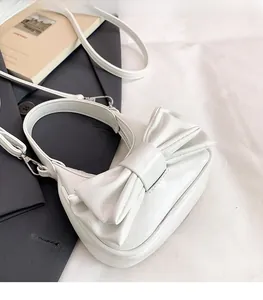 Close-up of white mini handbag featuring textured faux leather and a large bow detail