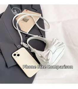 Mini white bow handbag with ruched texture shown with a smartphone for size scale