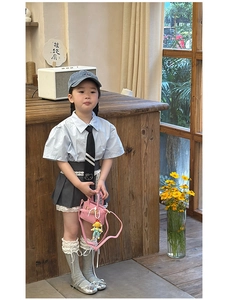 Detailed view of child model wearing a pink crossbody bag and academy style outfit