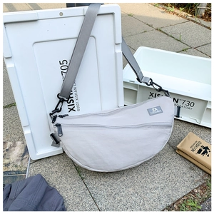 Gros plan sur le sac bandoulière en nylon gris clair avec double fermeture éclair