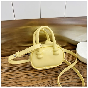 Vue détaillée du mini sac bowling jaune avec poignées et bandoulière réglable assortie