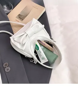 Mini white bow handbag interior showing storage capacity for cosmetics and daily items