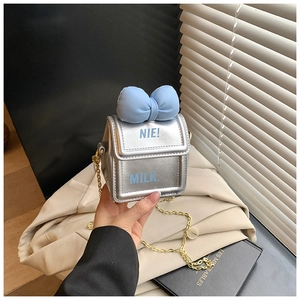 Détail du sac boîte à lait argenté avec nœud bleu clair et bandoulière chaîne dorée