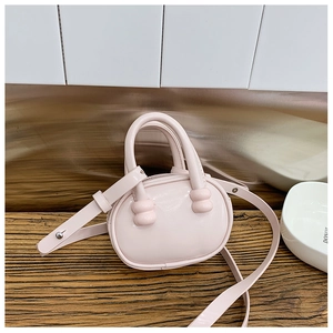 Détail du mini sac bowling rose clair avec finition brillante et poignée ondulée