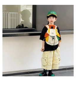 Kid's canvas backpack with colorful patchwork design shown on an Asian boy in outdoor setting