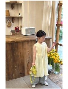 Toddler girl in yellow pleated sleeveless top and blue wide-leg jeans with mini handbag