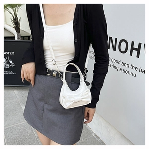 Modern white mini handbag with bow detail shown in a stylish street style outfit
