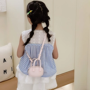 Mini sac à bandoulière rose pour enfants porté avec un haut à carreaux et jupe dentelle