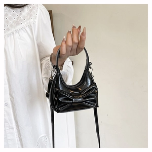 Detailed view of black bow-knot handbag with glossy finish and elegant hand-held strap