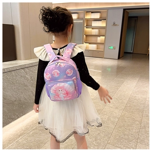 Rear view of a child wearing the purple mermaid backpack in a well-lit indoor hallway