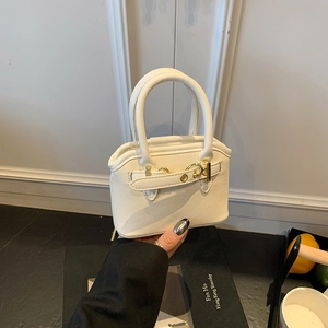 Detail of mini cream canvas handbag with gold metal clasp and smooth leather handle