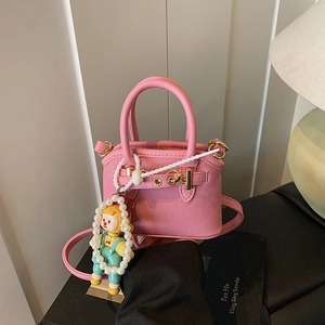 Detailed close-up of pink mini shell bag with gold clasp and cute cartoon pearl pendant