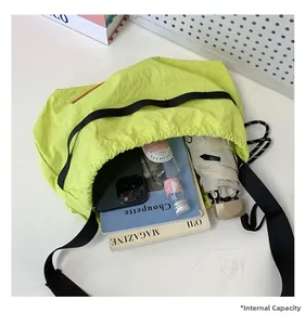 Spacious interior of neon yellow nylon crossbody bag holding a phone, bottle, and book