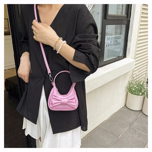 Close-up of pink glossy mini handbag with oversized bow detail and top handle