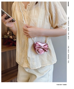 Detail of pink laser heart bag with oversized bow and elegant faux pearl chain strap