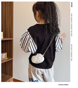 Dettaglio della borsa a cuore con catena dorata su outfit alla moda per bambine