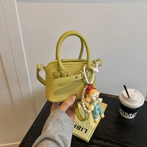 Detailed shot of lime green shell bag with woven texture and cute cartoon pearl charm