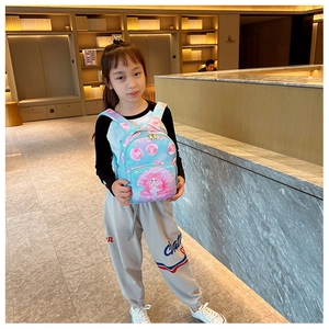 Girl wearing blue mermaid school bag with pink shell pattern in a modern indoor setting