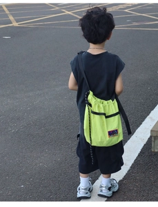 Detail view of neon green drawstring kid shoulder bag with mountain patch and adjustable strap