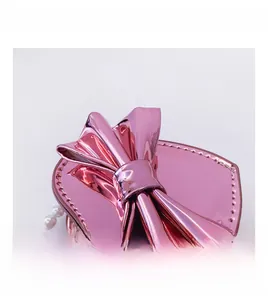 Detail of pink laser surface finish on girls' mini bow bag with white pearl chain
