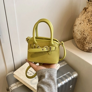 Detailed view of the mini green handbag's fine woven texture and golden metal buckle